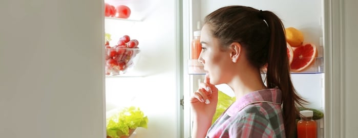woman looking in her fridge full of fruits and veggies
