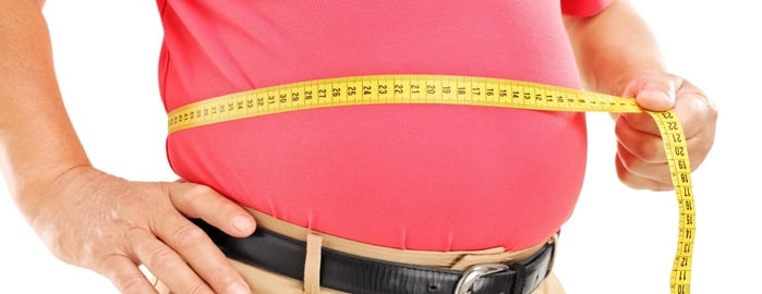 weight loss symbolized by a man measuring his tummy size with a measuring tape