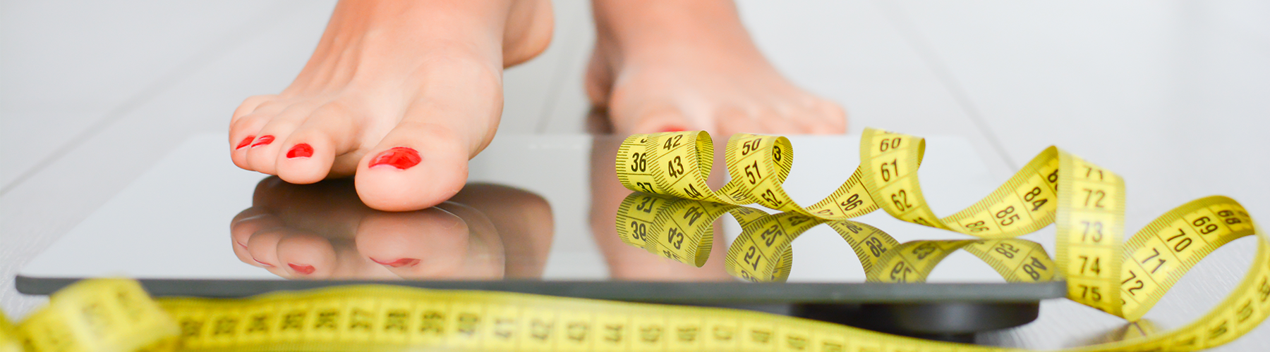 female feet on scare with measuring tape