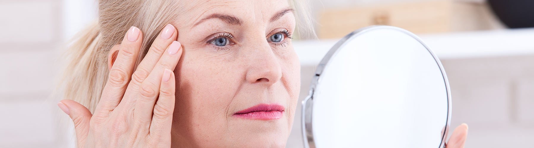Woman looking at wrinkles in a mirror