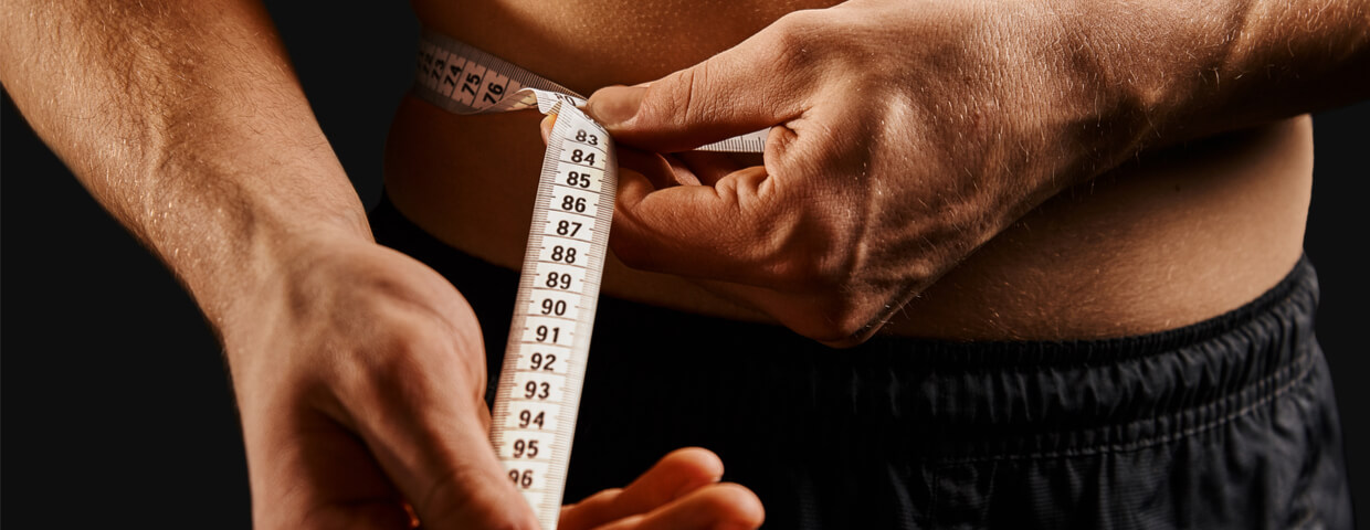 close up of a man measuring weight loss with tape