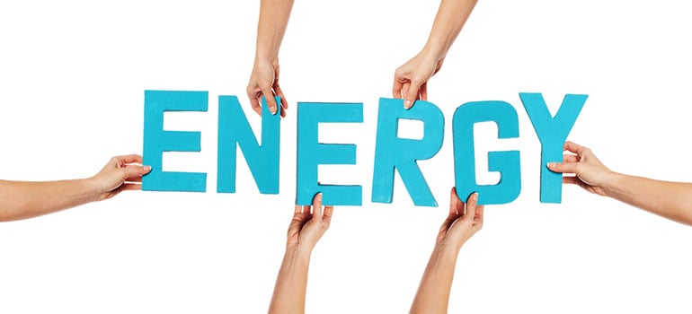 Letter cut outs spelling Energy being held up by hands