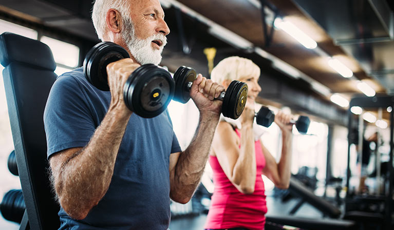 Elderly couple lifting weights in a gym