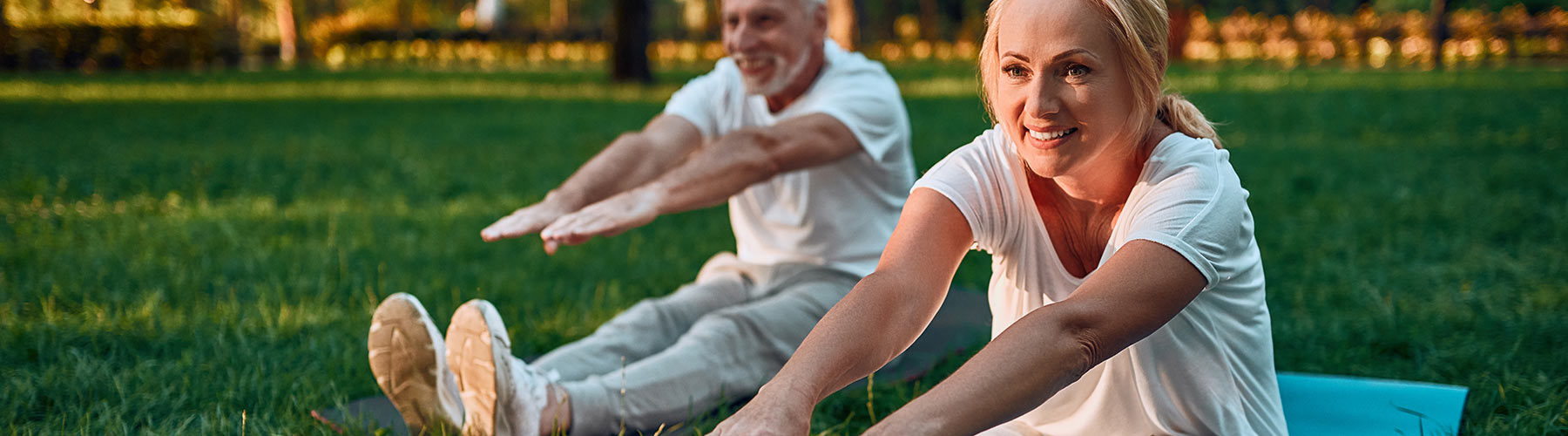 Middle aged couple stretching in park