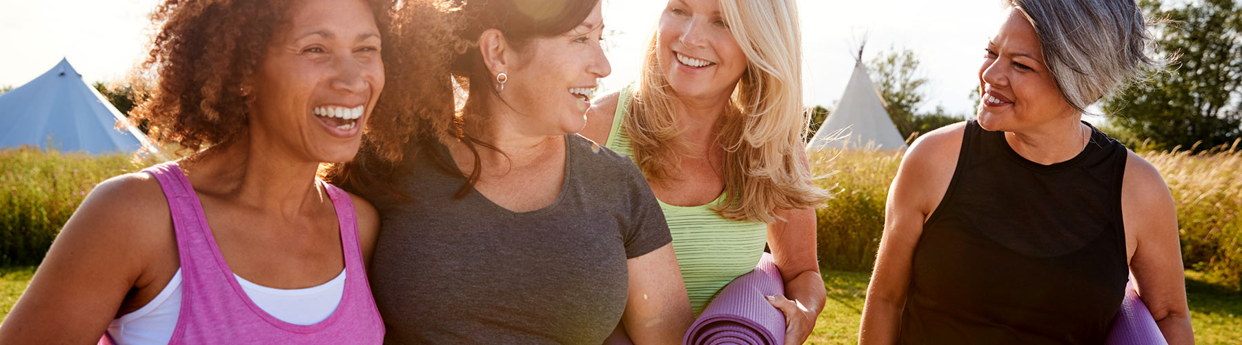 Group of women walking together in workout clothes holding yoga mats